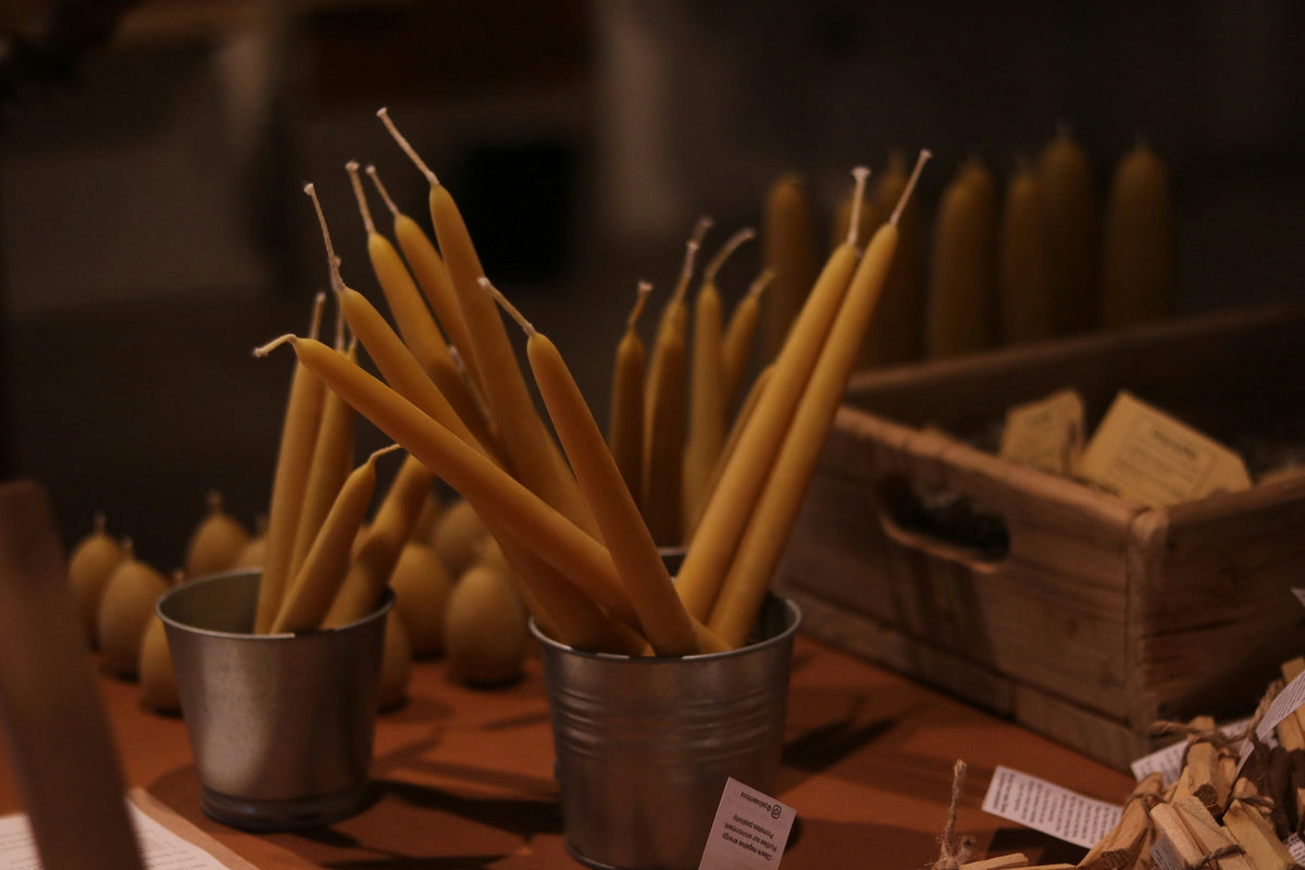 Beeswax taper candles in tin pots on a market stall
