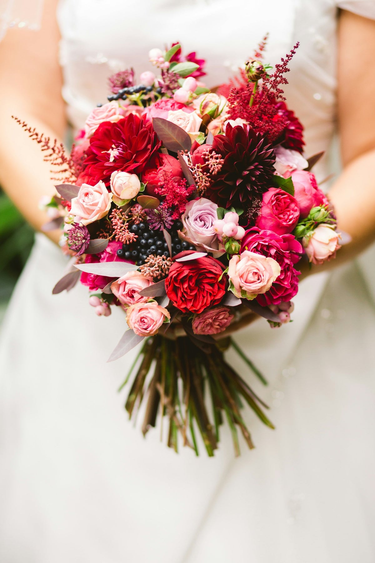Bride holding a bouquet of red roses, pink roses and berries