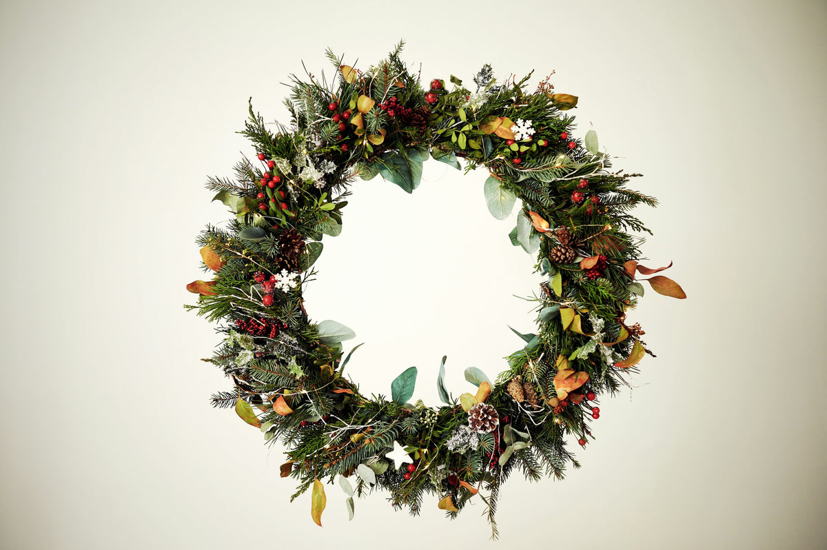 Festive foliage wreath with berries on a pale background