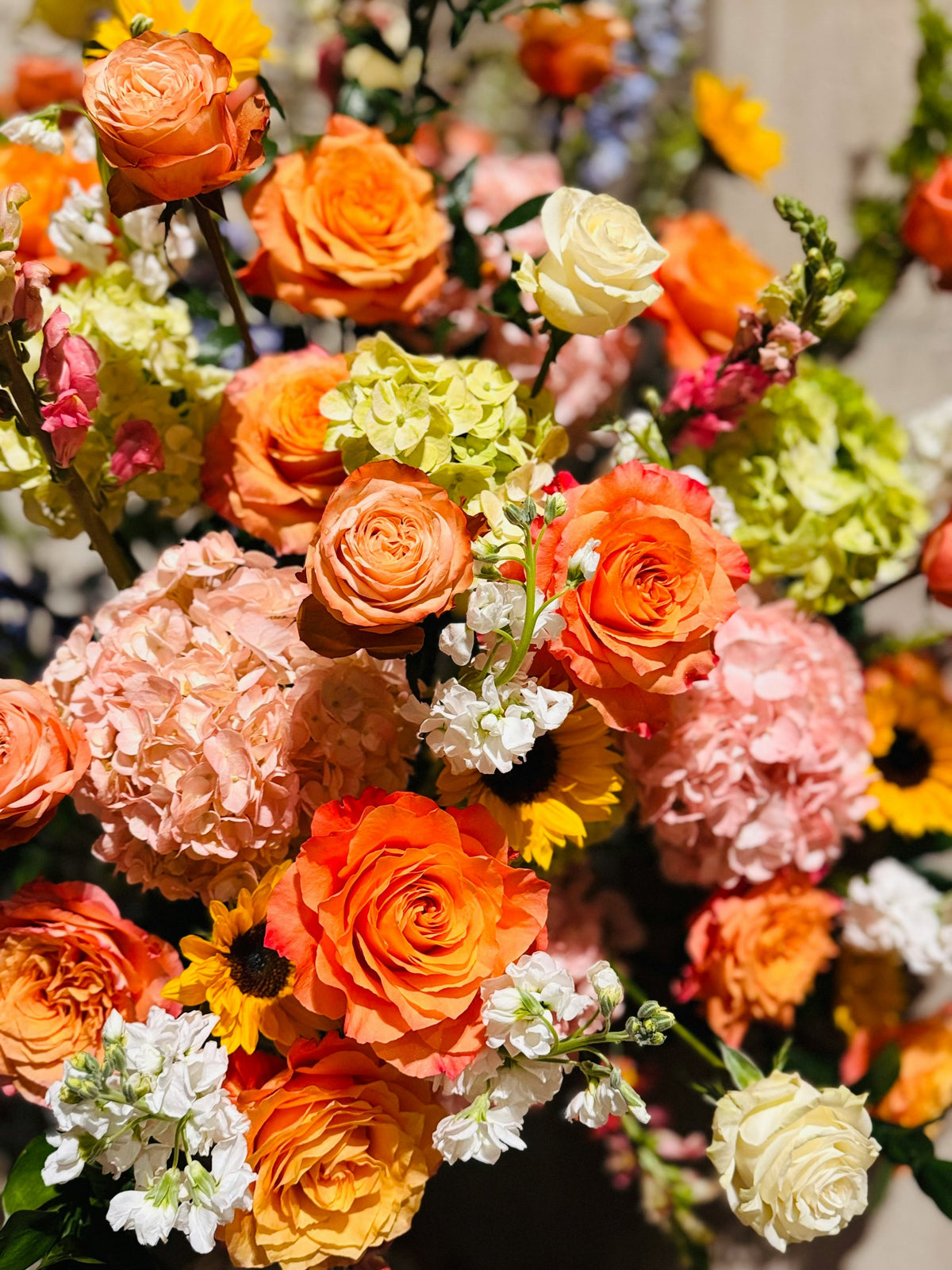 Arrangement of orange roses, peach hydrangea and sunflowers