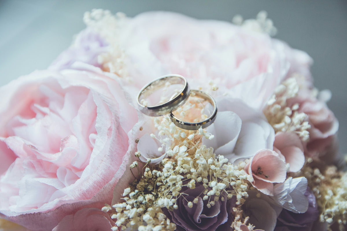 Wedding rings resting on a bouquet of pale pink peonies
