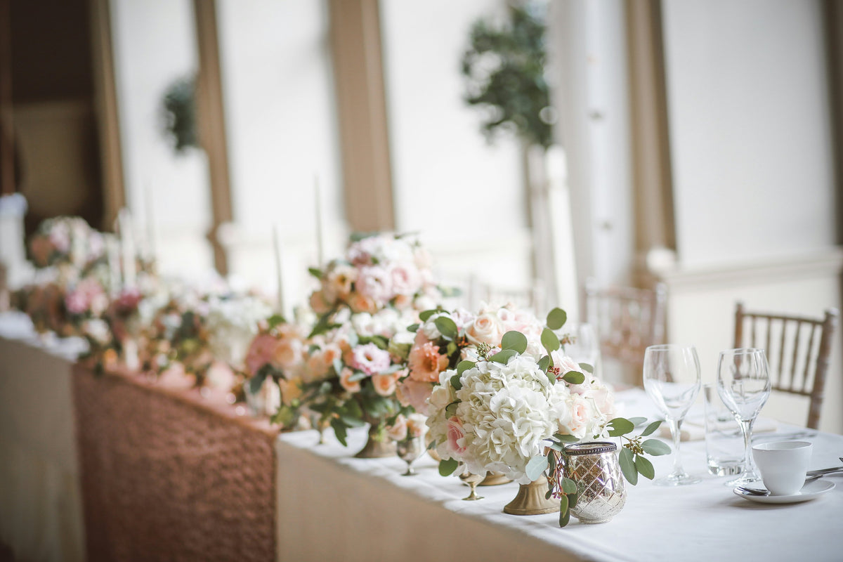 Wedding top table with low arrangements of white and blush flowers